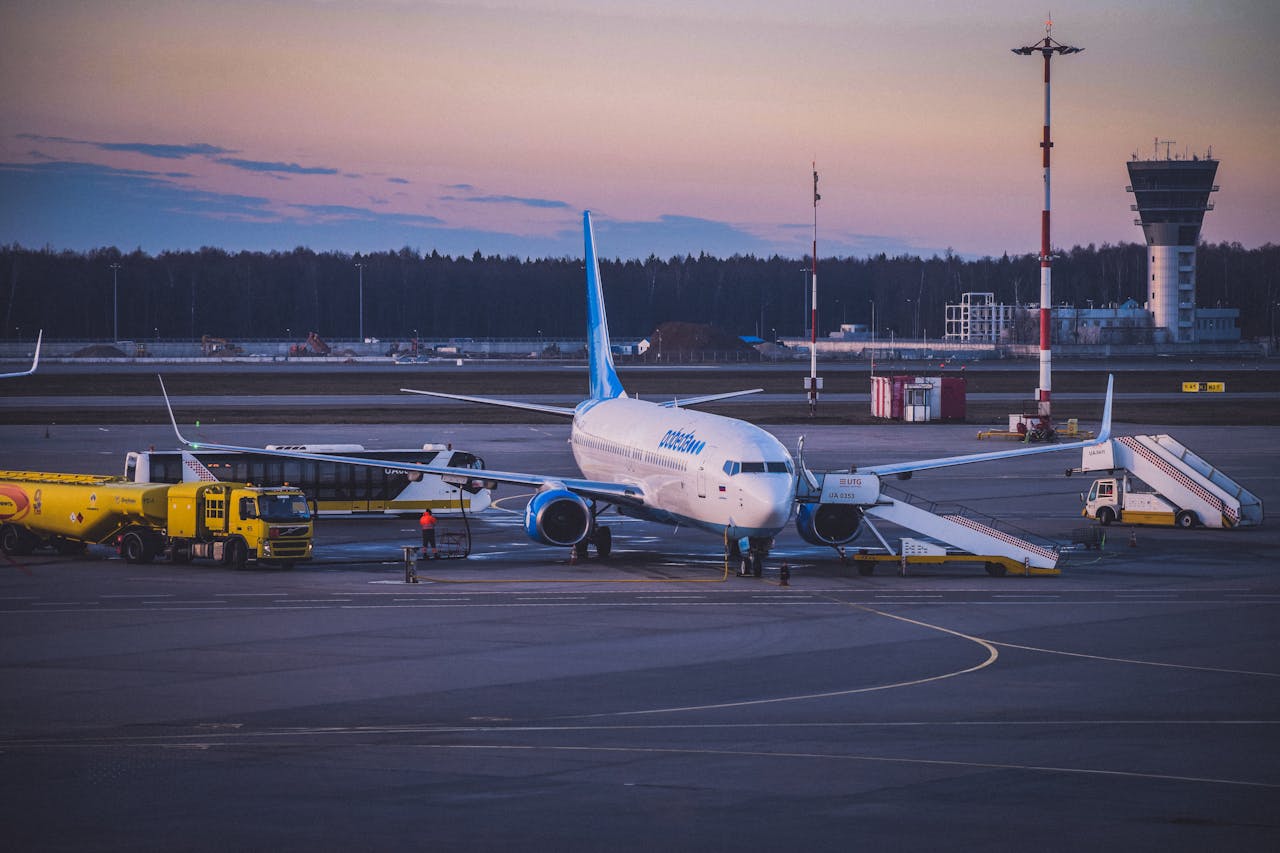Inicio Jet airplane parked at airport tarmac during twilight with refueling trucks and boarding stairs