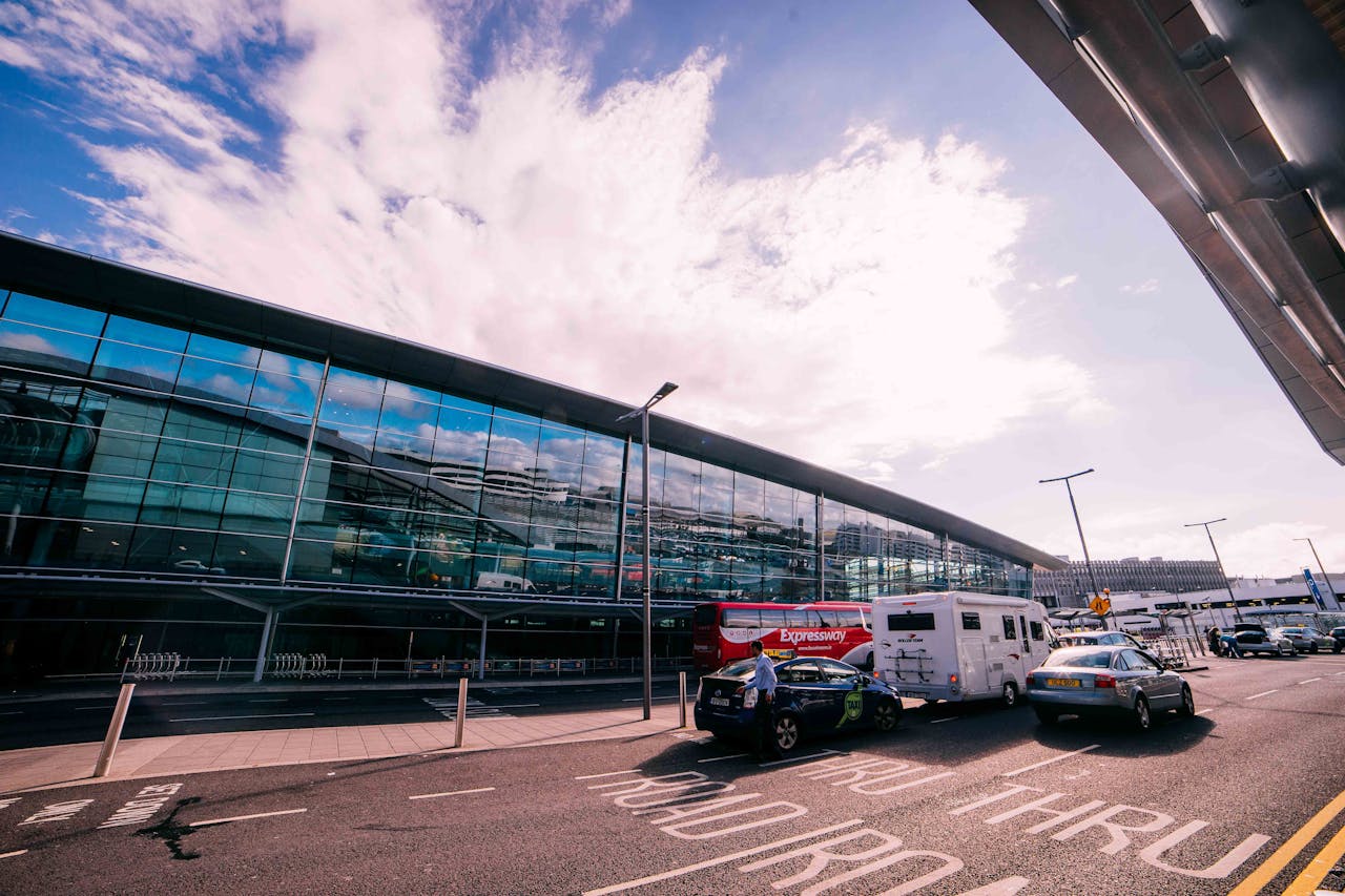 About Daytime view of the modern terminal building at Dublin Airport, Ireland, with cars and buses parked outside.